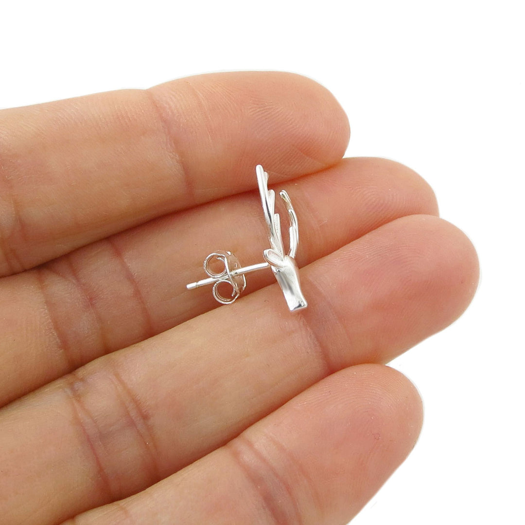 A large 925 sterling silver stag or deer head and antlers stud earring held on a person's fingers against a plain white background.