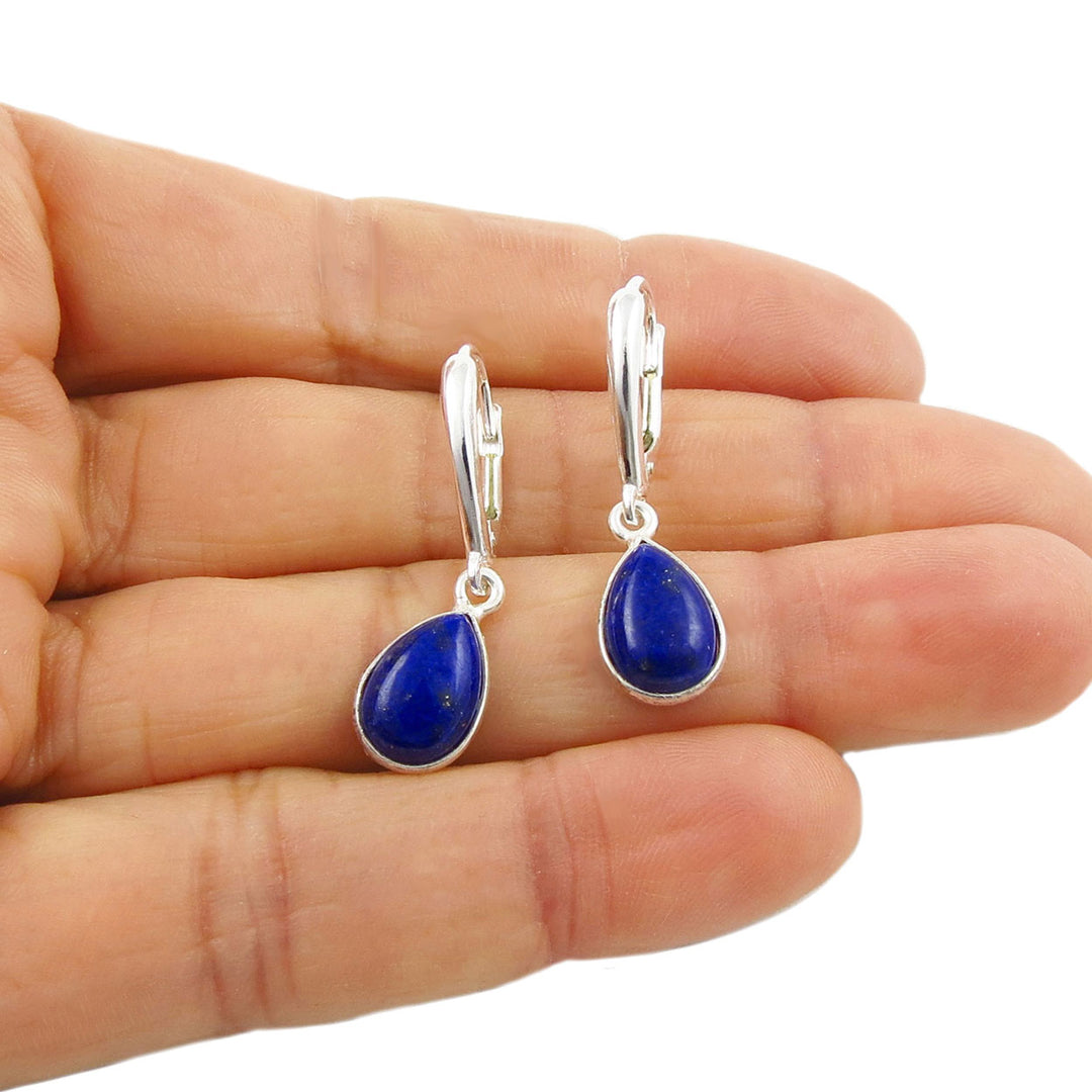Sterling 925 Silver lever back earrings with blue lapis lazuli gemstones held in a woman's hand on a white background