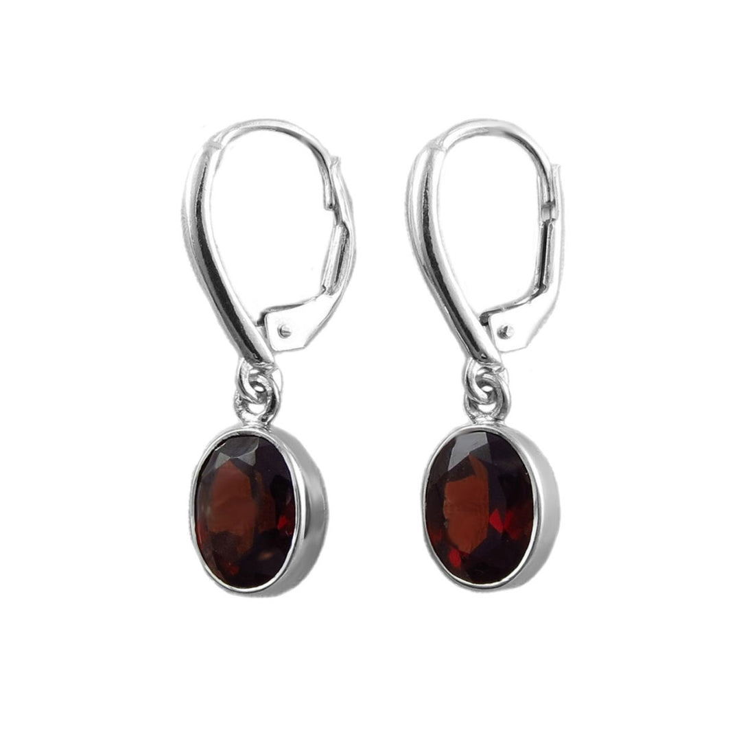 A pair of sterling 925 silver lever-back drop earrings featuring faceted oval dark red garnet gemstones in silver bezel settings, shown against a plain white background.