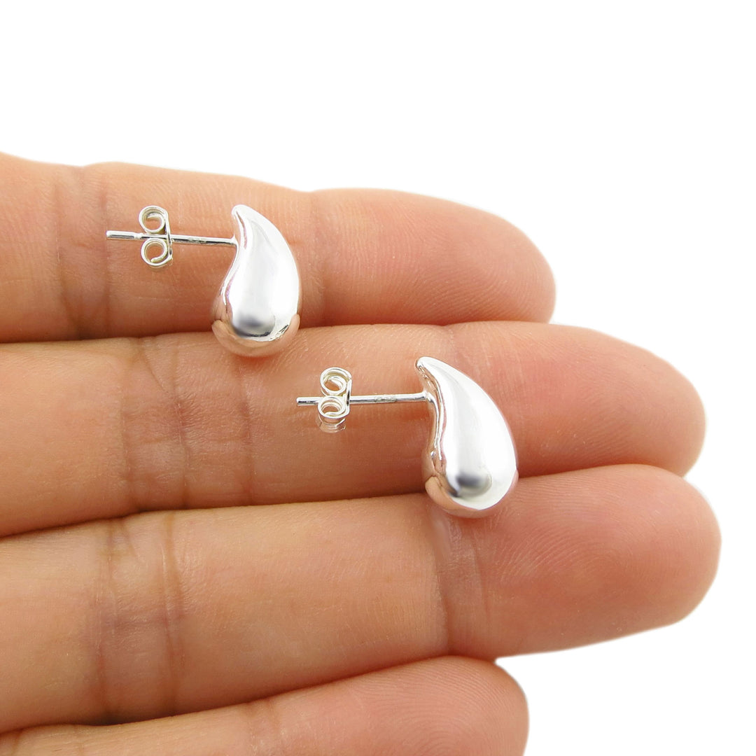 A pair of polished 925 silver teardrop-shaped stud earrings displayed on a woman's fingers against a plain white background.