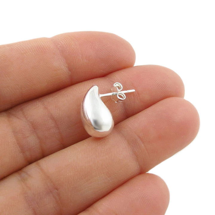 A polished sterling 925 silver teardrop-shaped stud earring held on a woman's fingers against a plain white background.