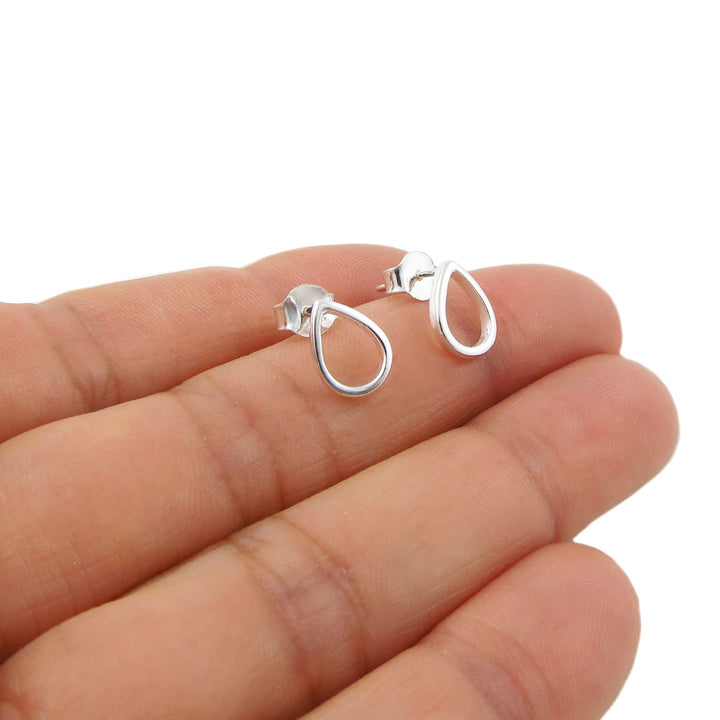 A pair of polished 925 silver teardrop-shaped hoop earrings held on a person's fingers against a plain white background.