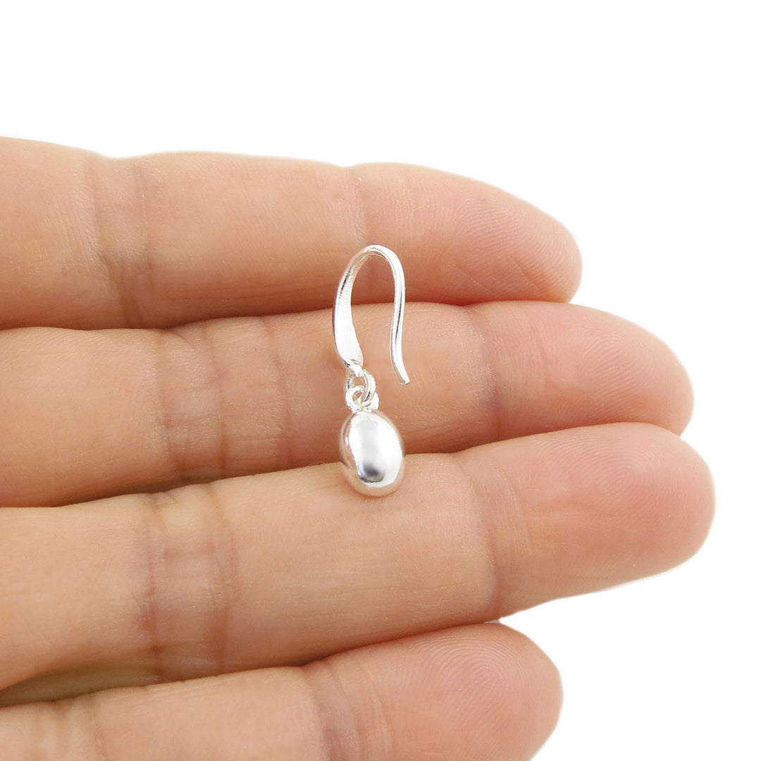 A small 925 silver dangle coffee bean design earring held between fingers against a plain white background