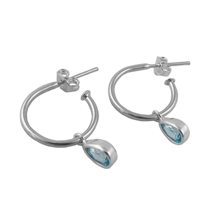A pair of 925 silver hoop earrings with teardrop-shaped light blue March birthstone aquamarine gemstone drops, shown on a plain white background.