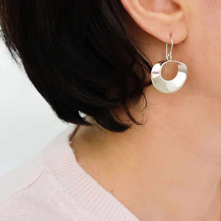 Large 925 sterling silver mobius hoop earrings worn by a woman with a neutral background