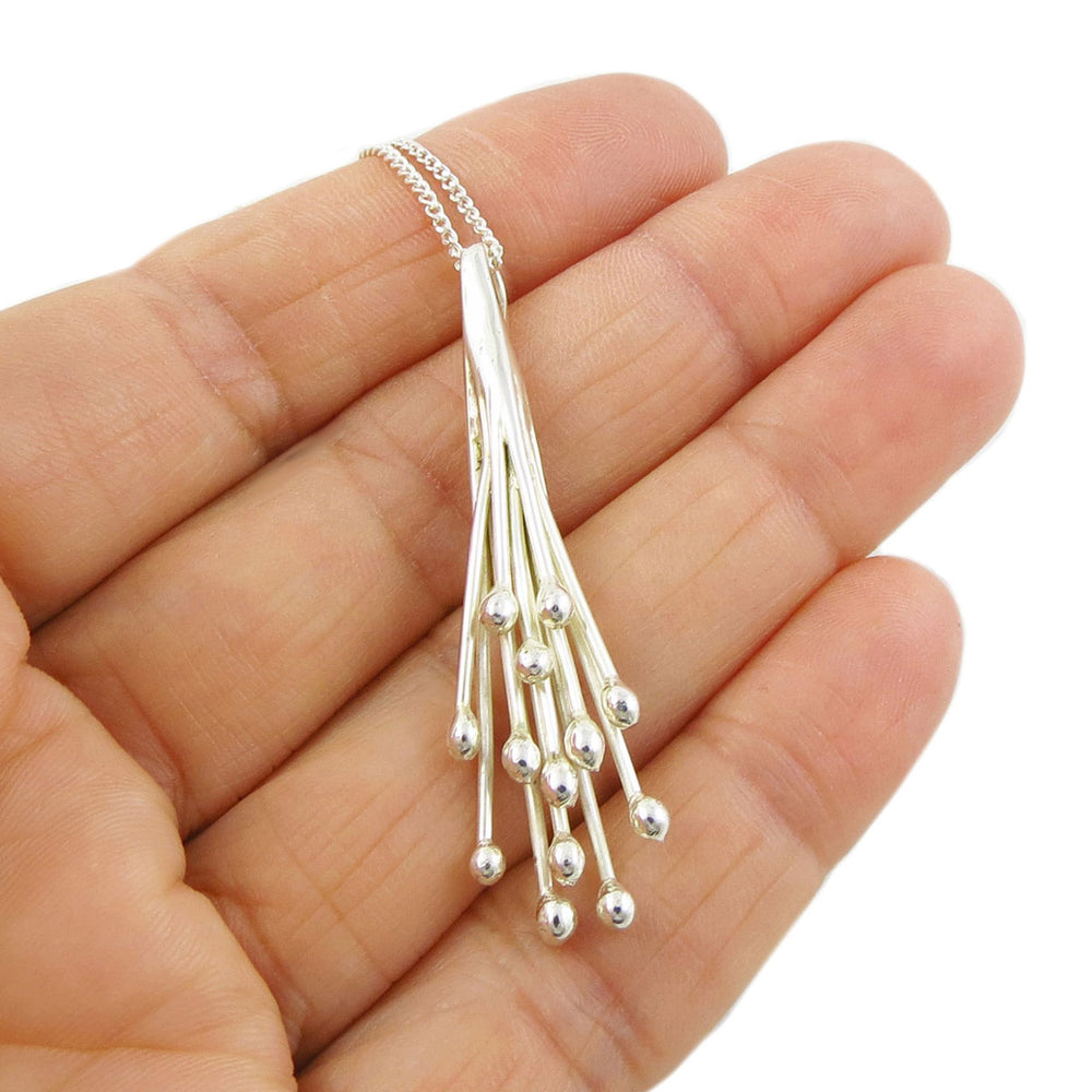 Long Mexican 925 sterling silver pendant and chain necklace featuring a waterfall cluster design held in a female hand. 