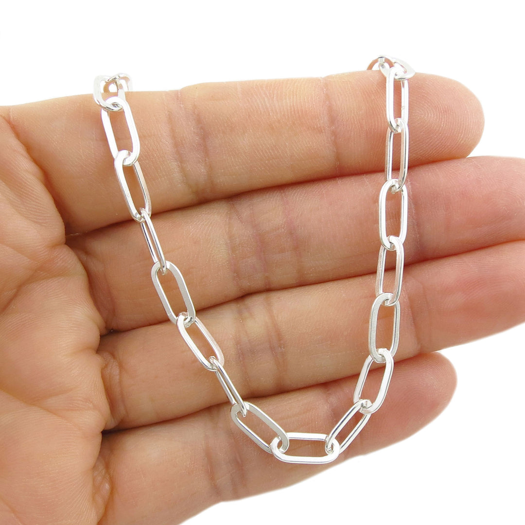 Sterling silver curb chain held in a hand against a white background