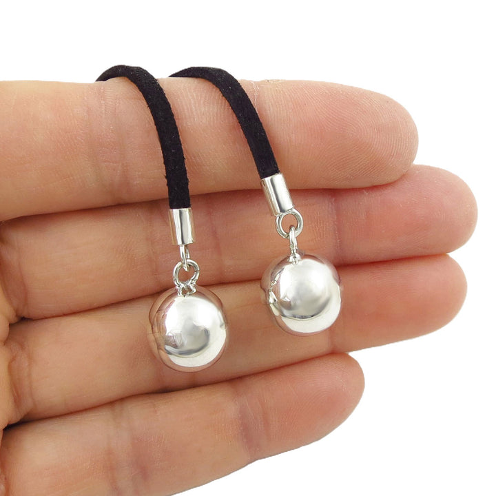 Silver ball bead necklace on a black suede cord held between fingers against a white background