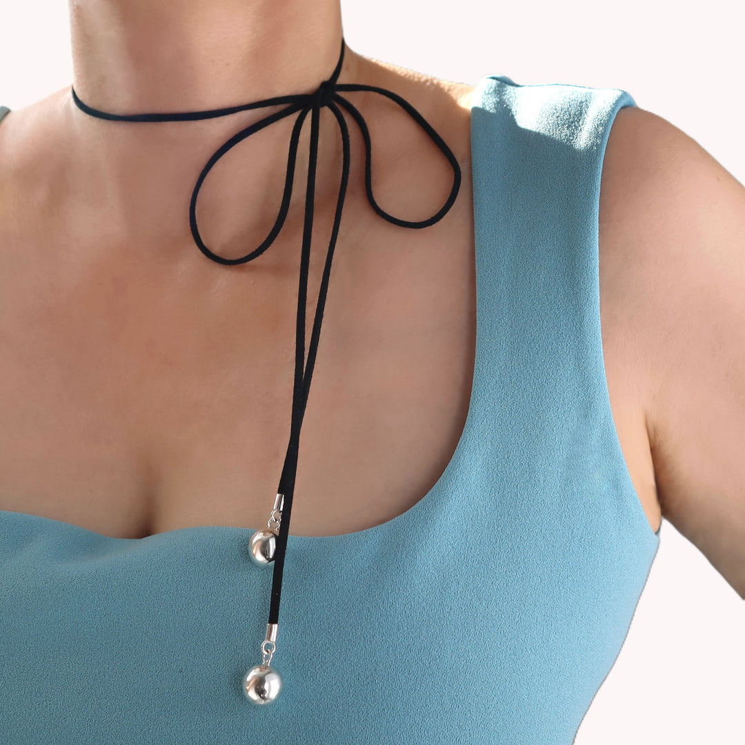 Black choker necklace with silver ball beads worn by a person in a blue top.