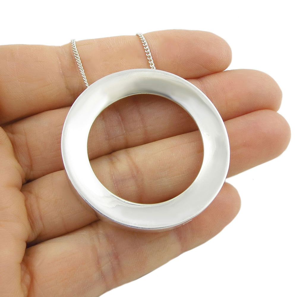 Silver ring pendant held in a hand against a white background