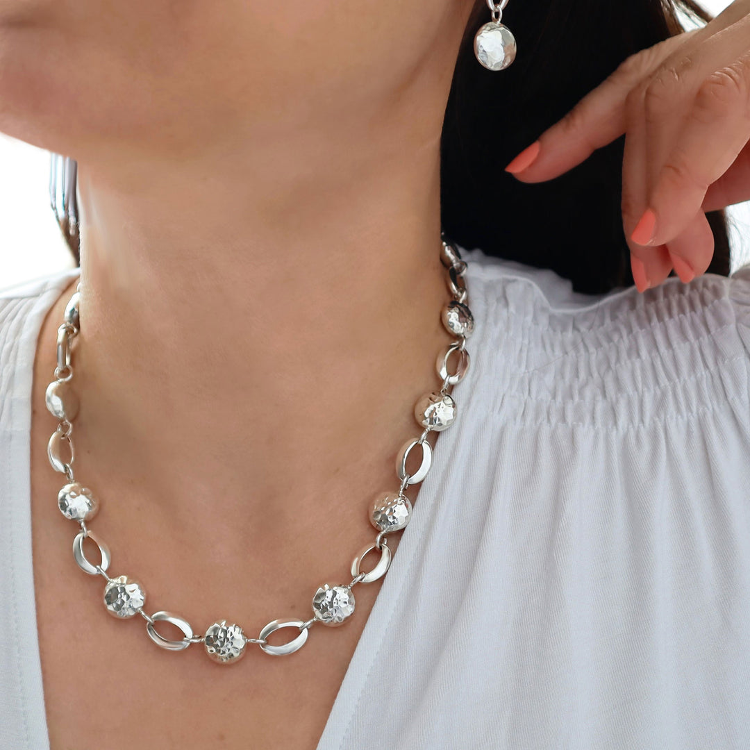 Fancy link silver necklace worn by a person with a blurred background
