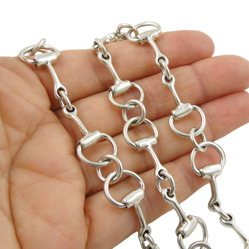 Silver chain horse snafflebit necklace held in a hand against a white background