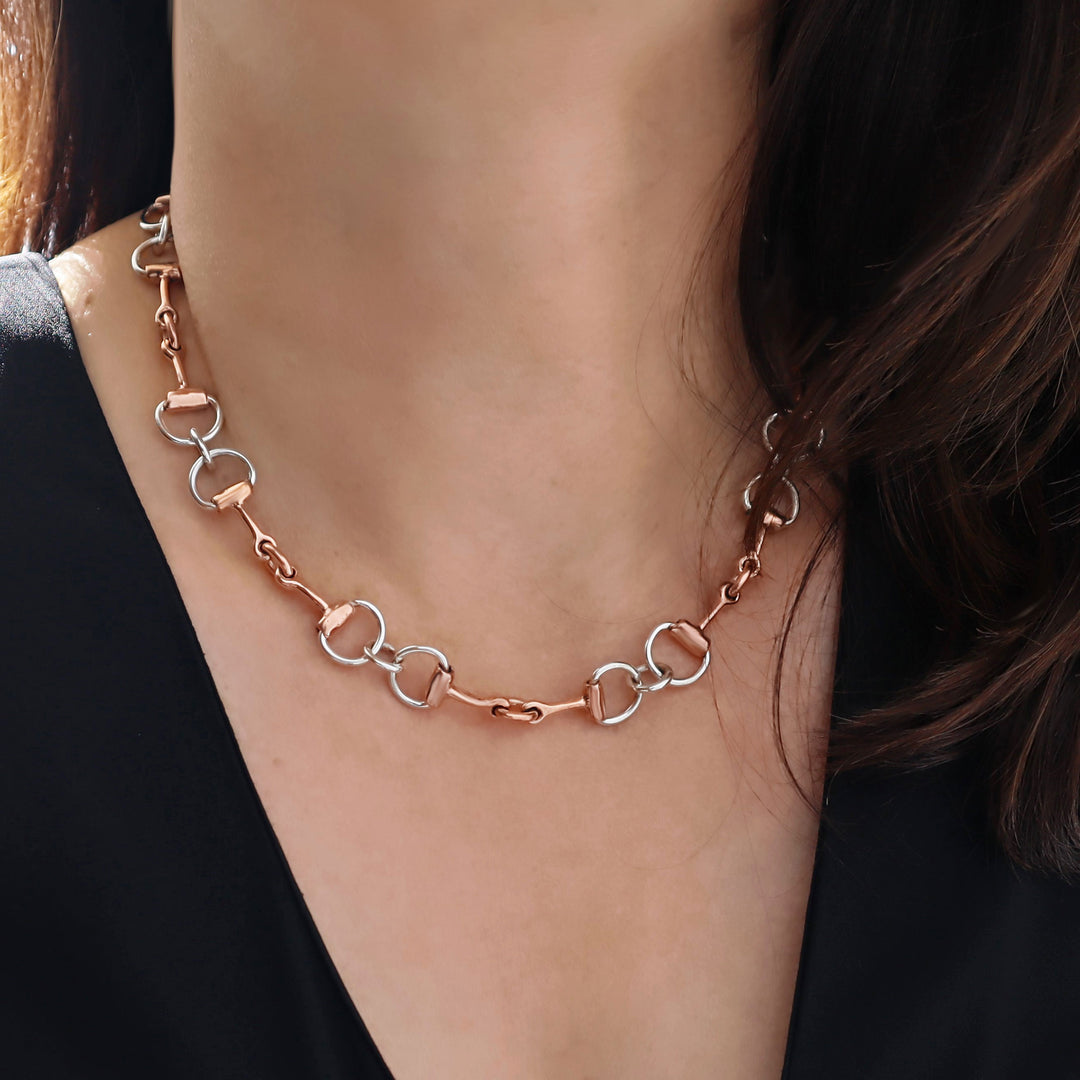 Copper horsebit chain necklace on a person wearing a black top