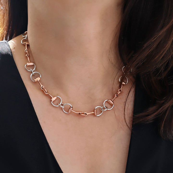 Copper horsebit chain necklace on a person wearing a black top