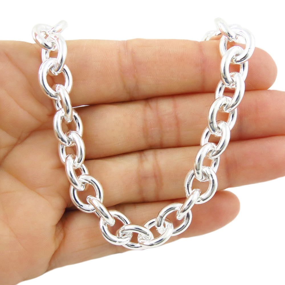 Silver chunky rolo chain bracelet held in a hand on a white background