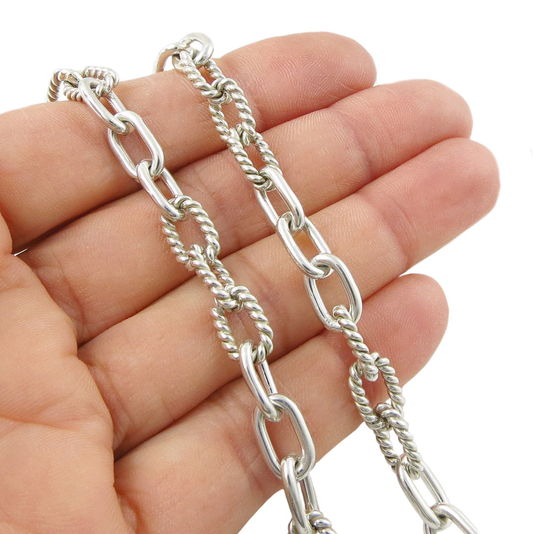 Silver chain held in a hand against a white background