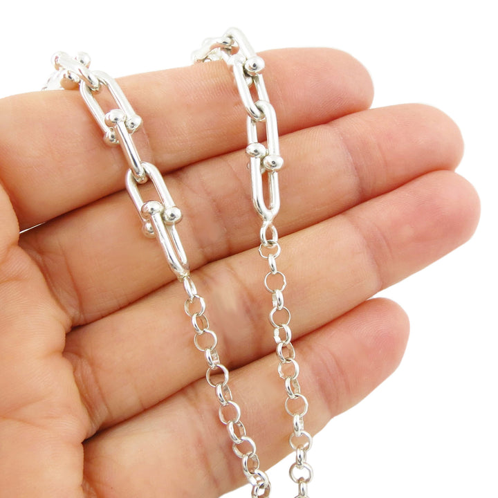 Sterling 925 Silver chain featuring circle and gauge links held between fingers on a white background