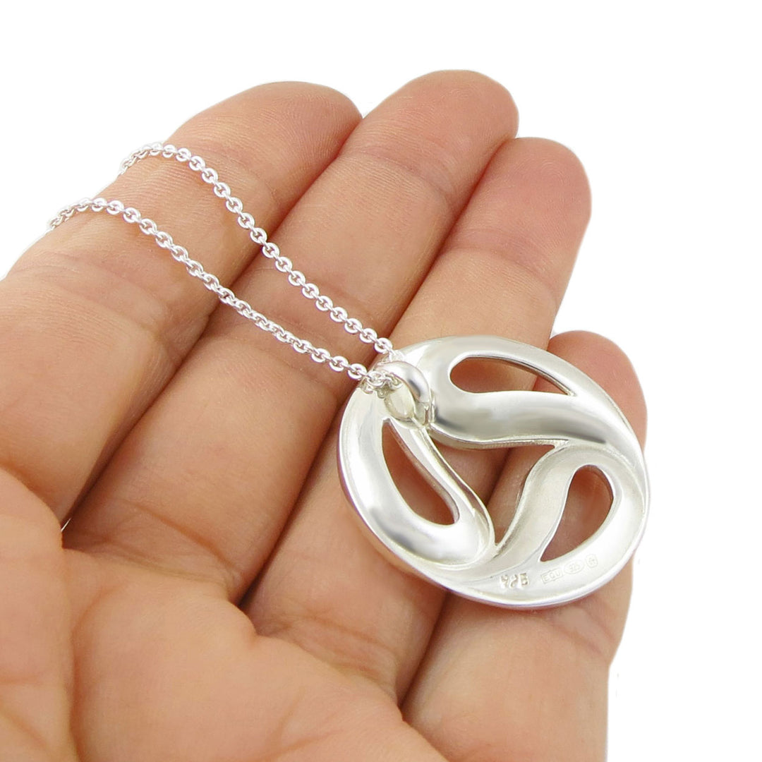 Reverse of a large sterling 925 silver necklace with a circular pendant held in a hand to how the 925 silver hallmark against a white background