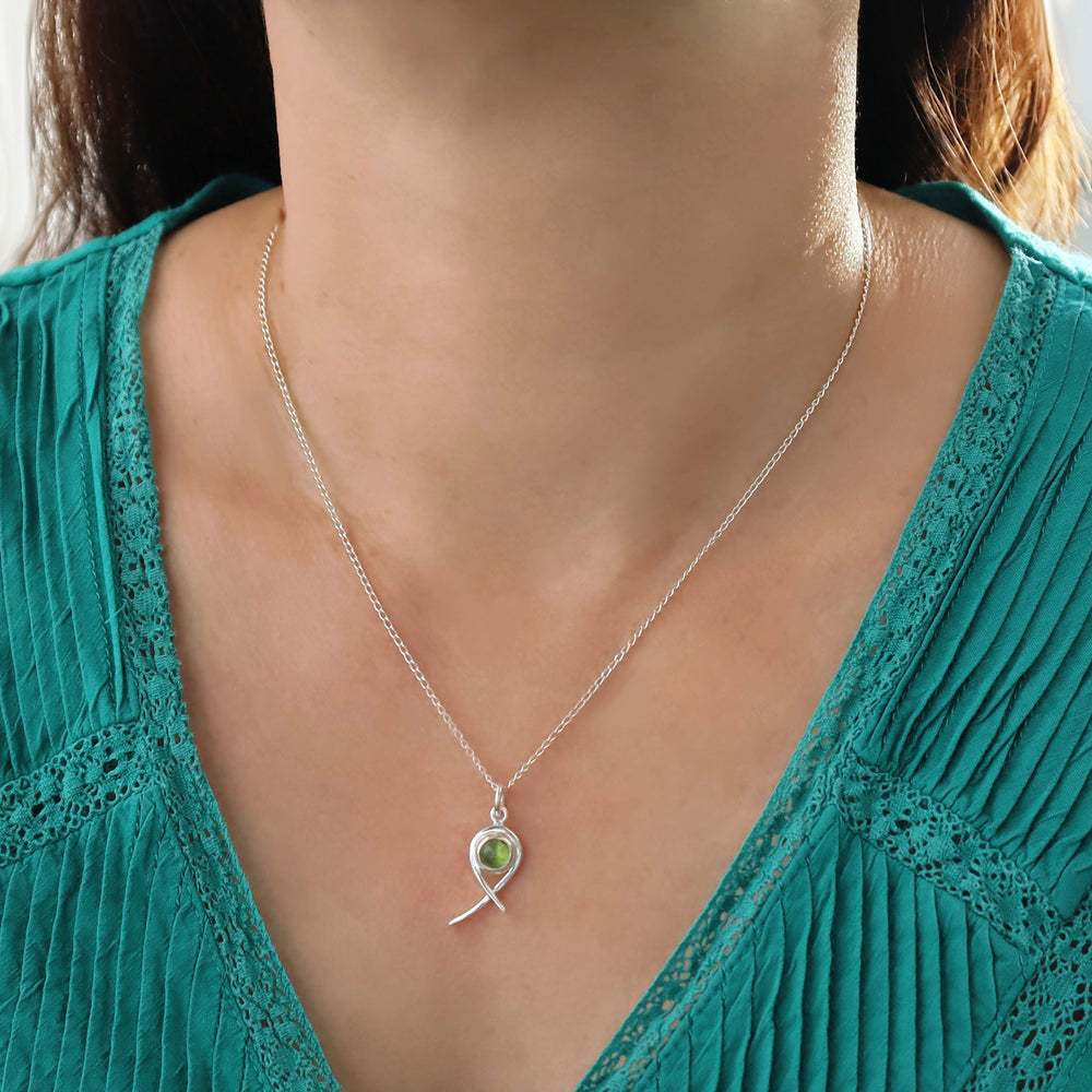 Necklace with a sterling 925 silver peridot gemstone pendant worn by a woman in a teal top