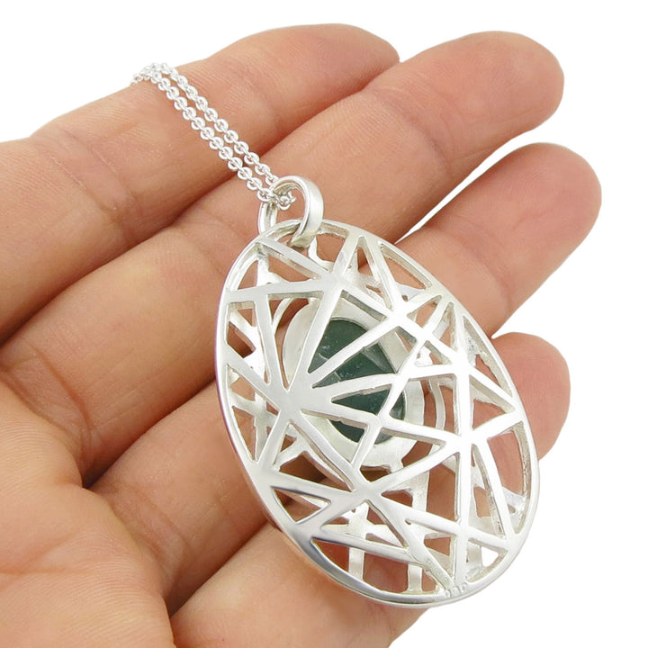 The reverse of a large 925 sterling silver pendant with an intricate geometric design held in a hand against a white background