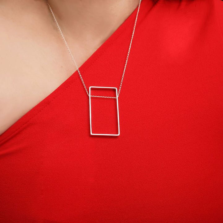 Unique modern 925 sterling silver necklace with a rectangular pendant worn by a woman in a red geometric top