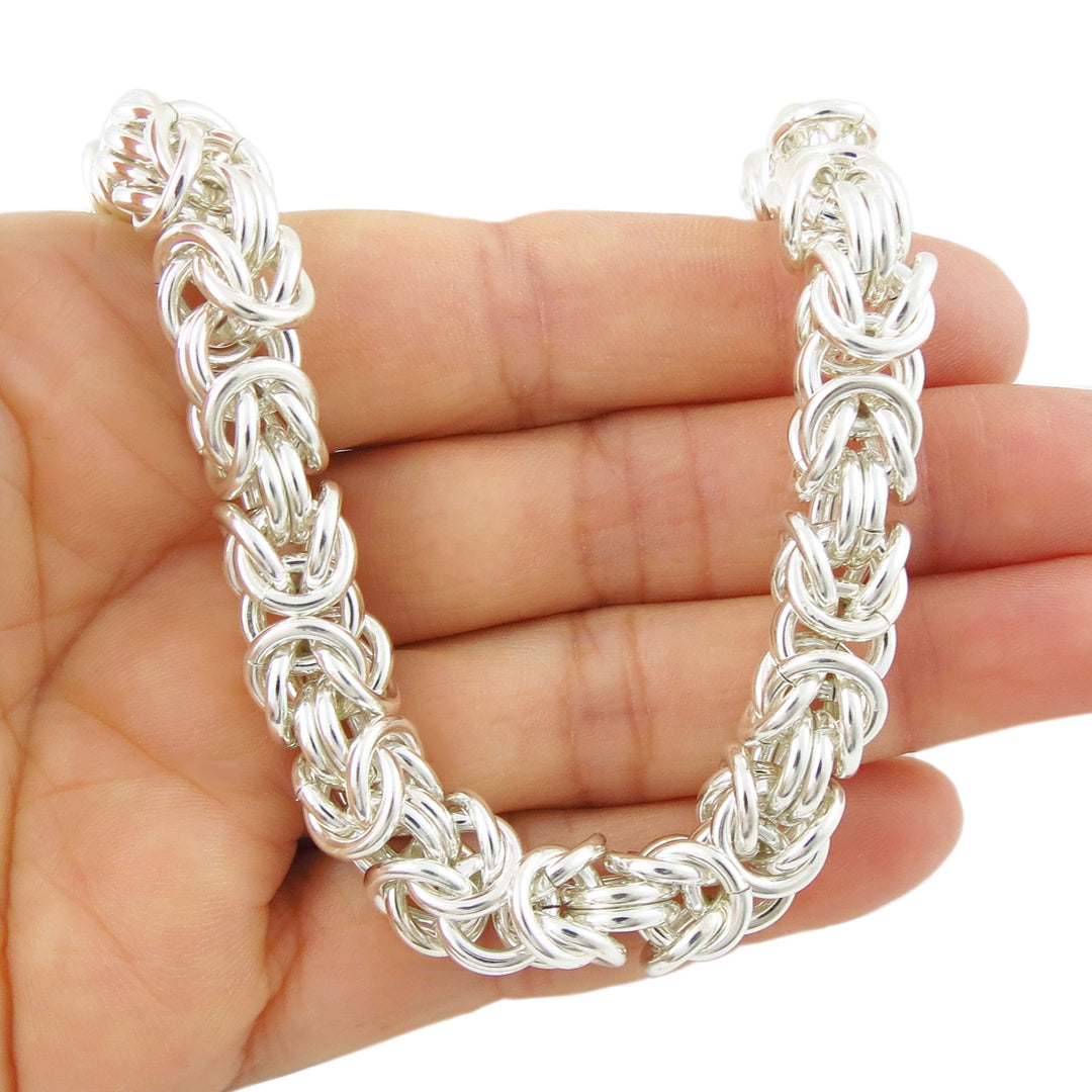 UK 925 sterling silver thick byzantine chain necklace on a hand with a white background