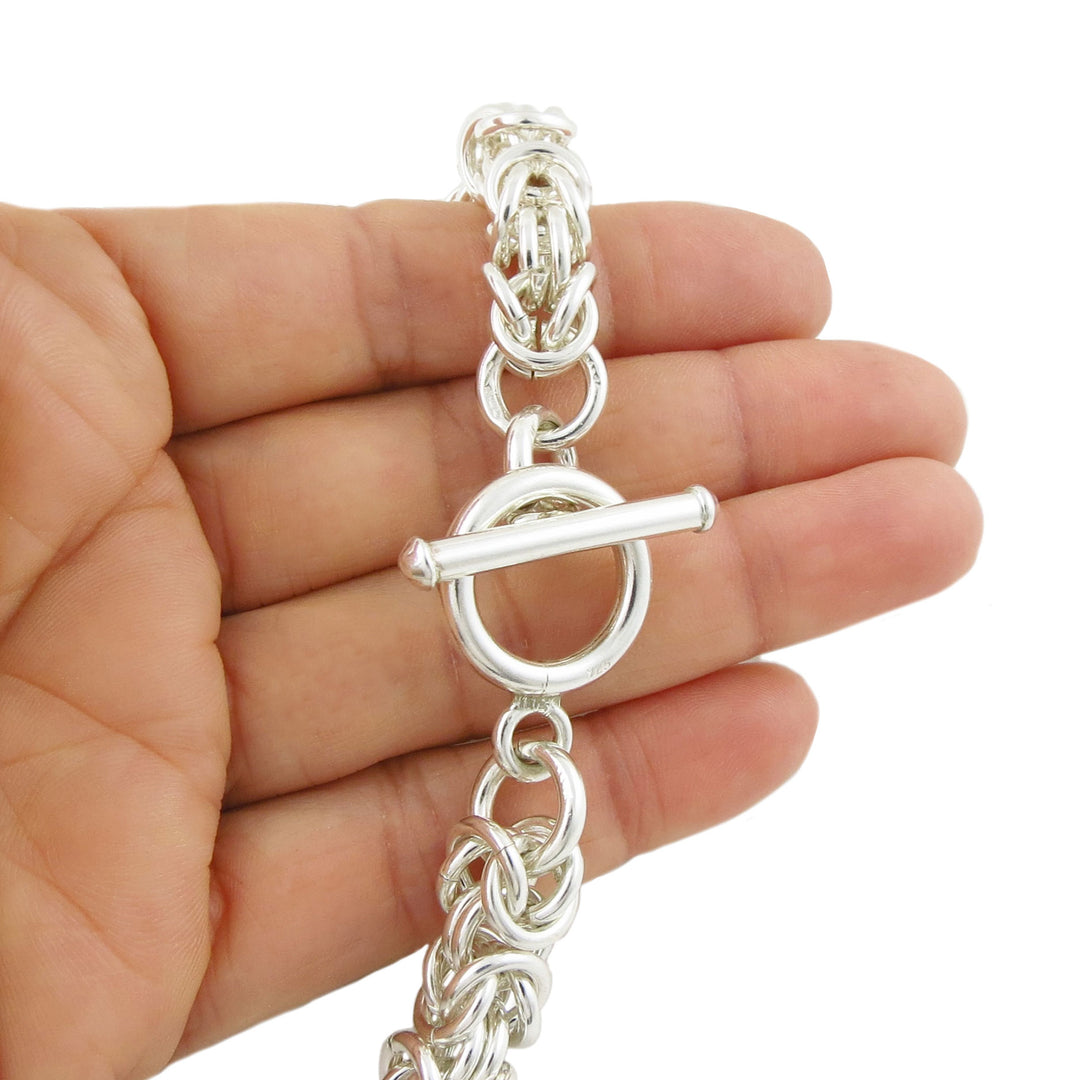 Sterling 925 silver byzantine chain necklace with a t bar toggle fastener held in a hand against a white background