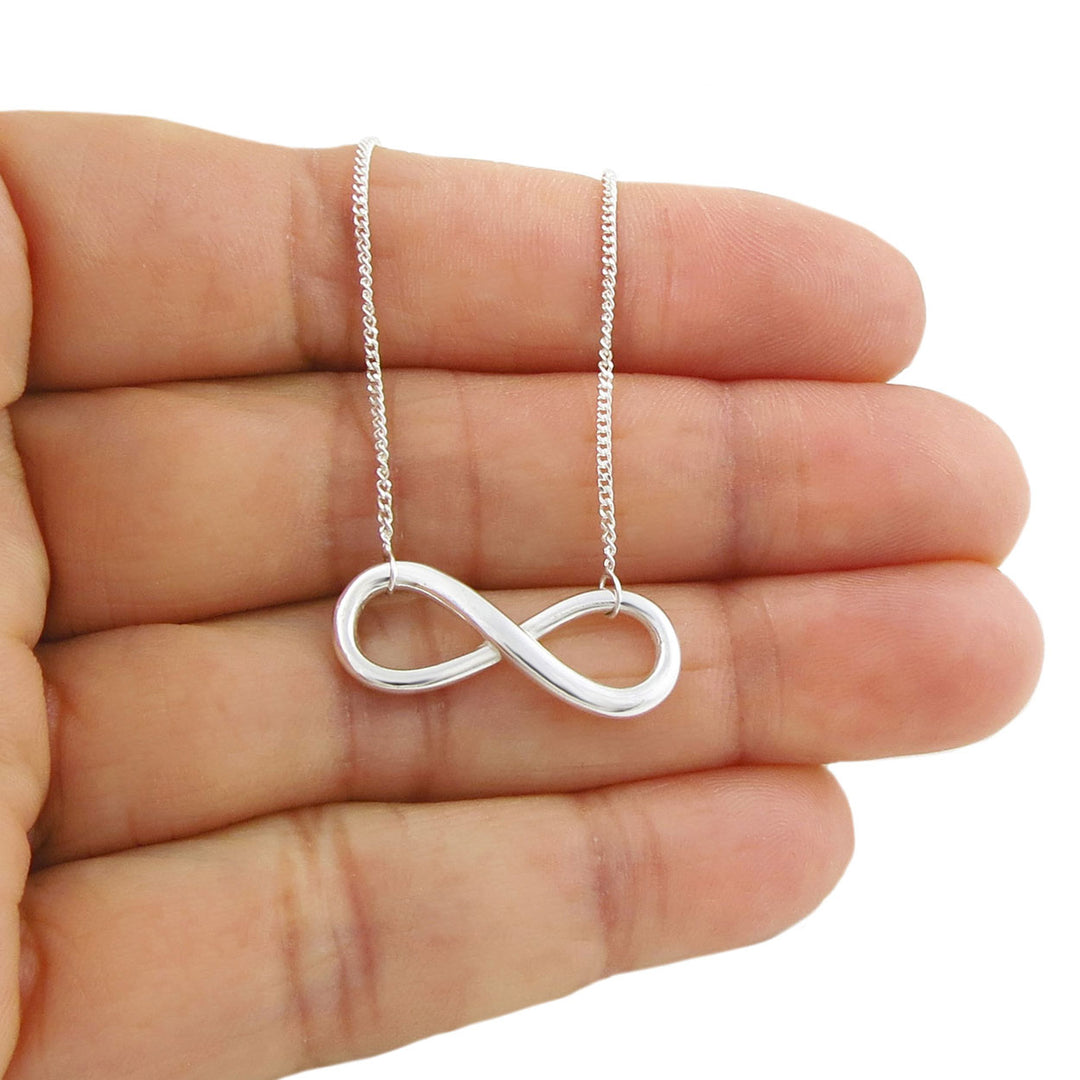 Infinity symbol pendant and chain necklace in sterling 925 silver held in  a person's hand
