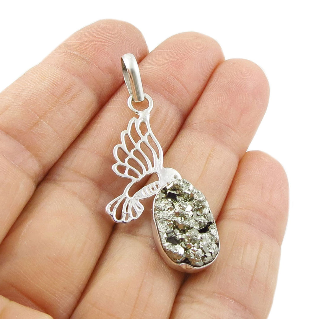 A gold-coloured pyrite gemstone bezel-set in a sterling silver base featuring a hummingbird motif. 