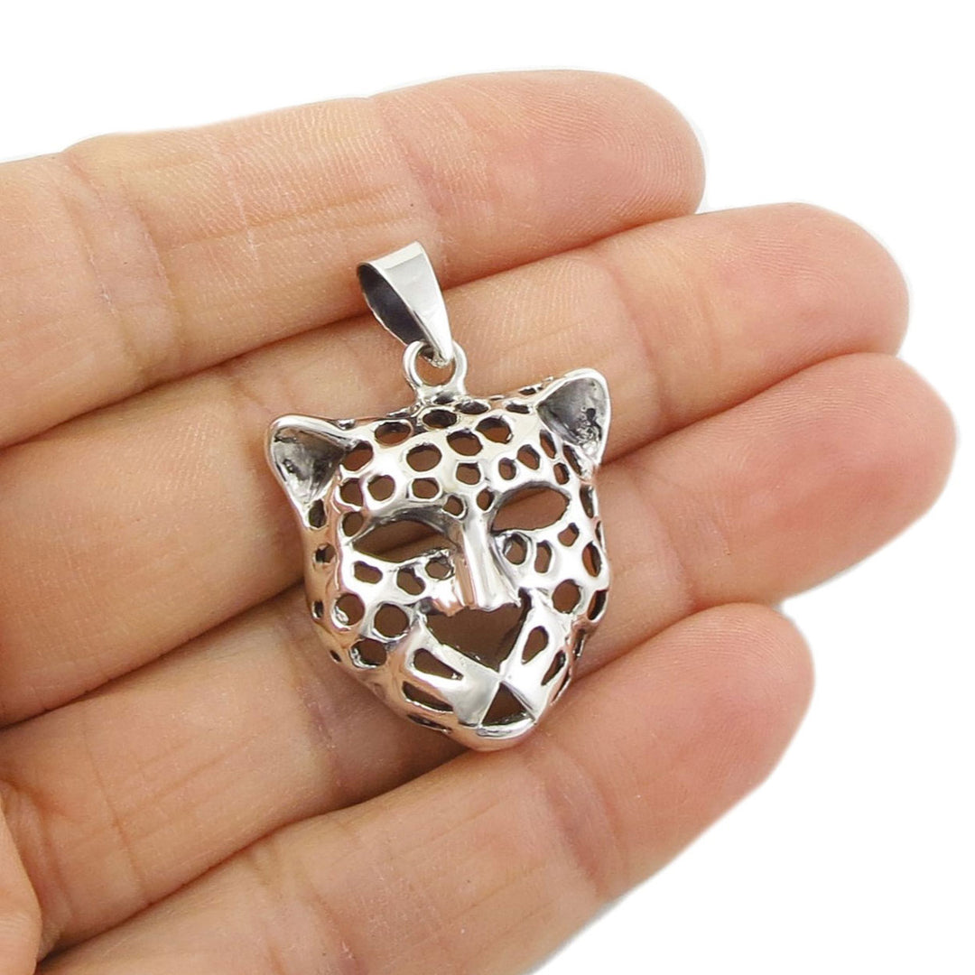 Sterling silver leopard head pendant held in a person's hand. 