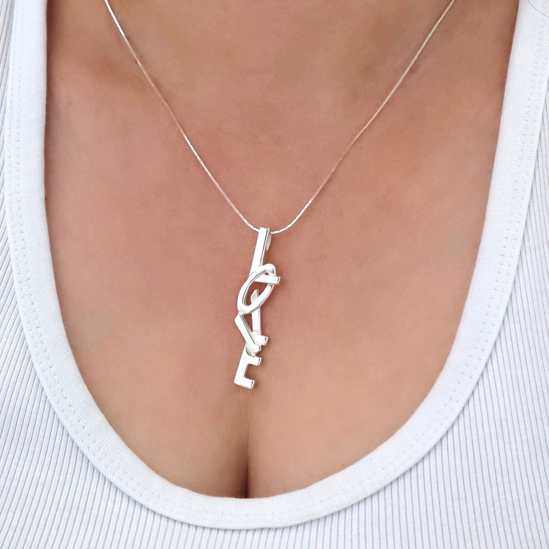 Silver necklace with a unique love pendant on a woman wearing a white top.