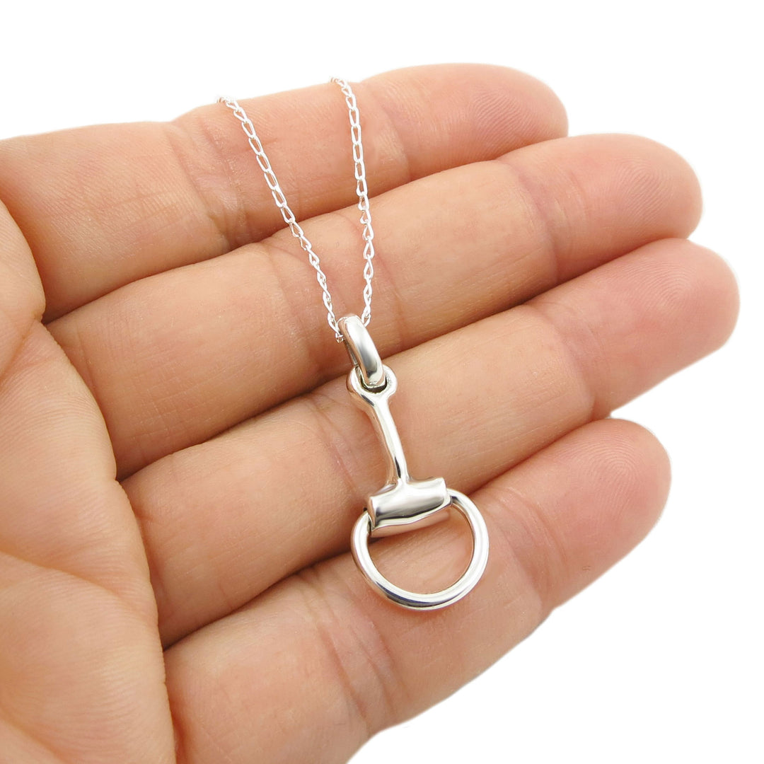 Silver horse bit necklace on a hand with a white background