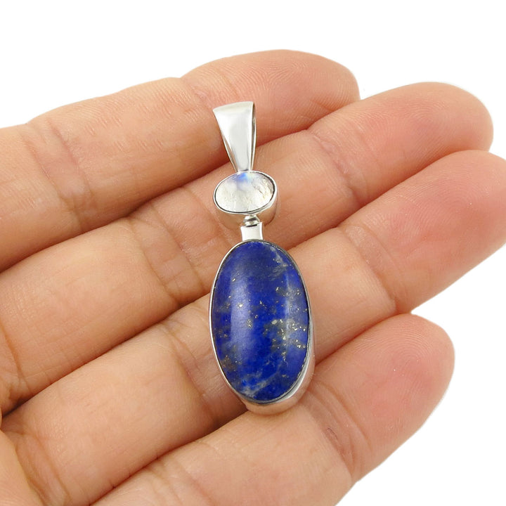 A lapis lazuli and moonstone gemstone pendant held in a person hand. 