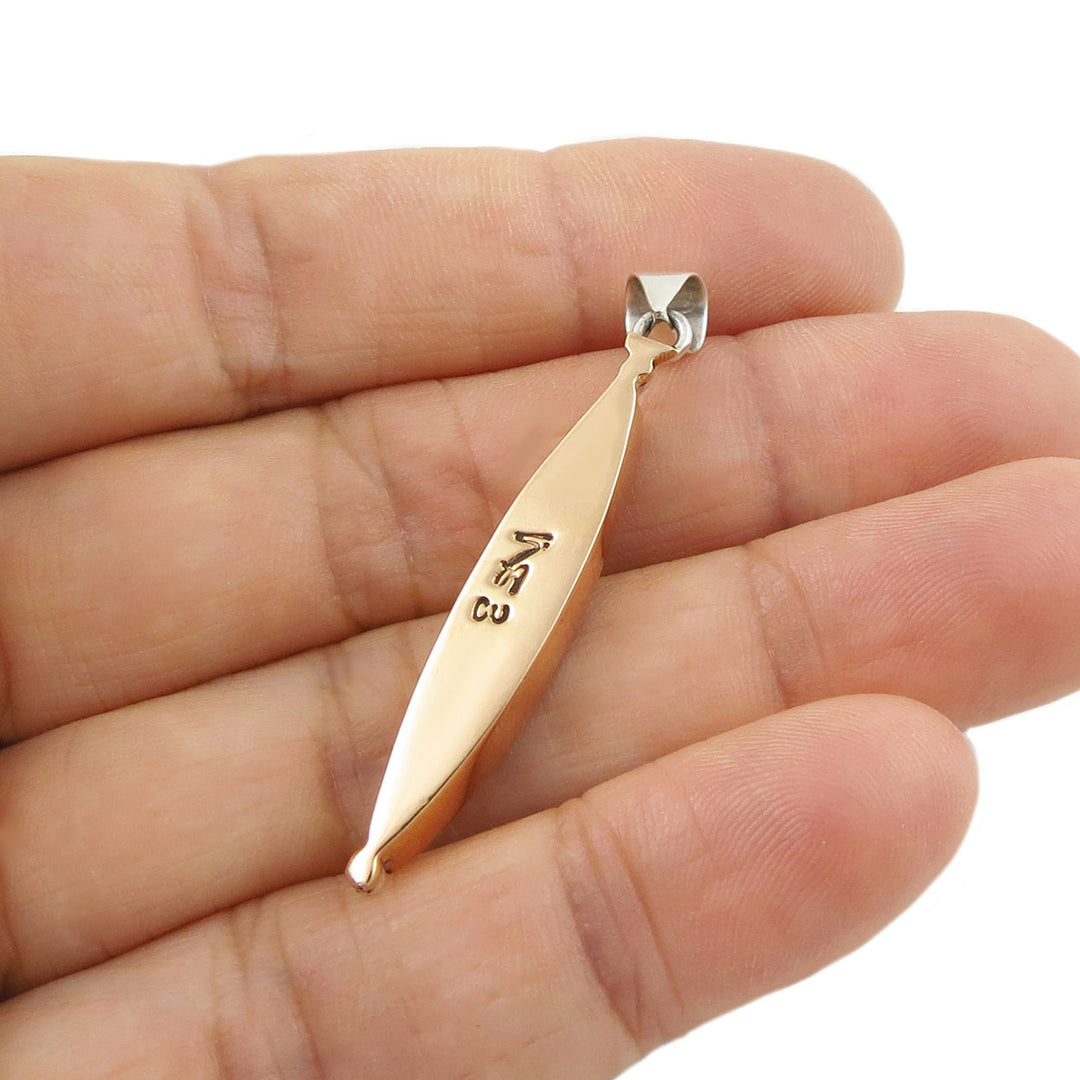 the reverse of a copper pendant held in a hand with a white background