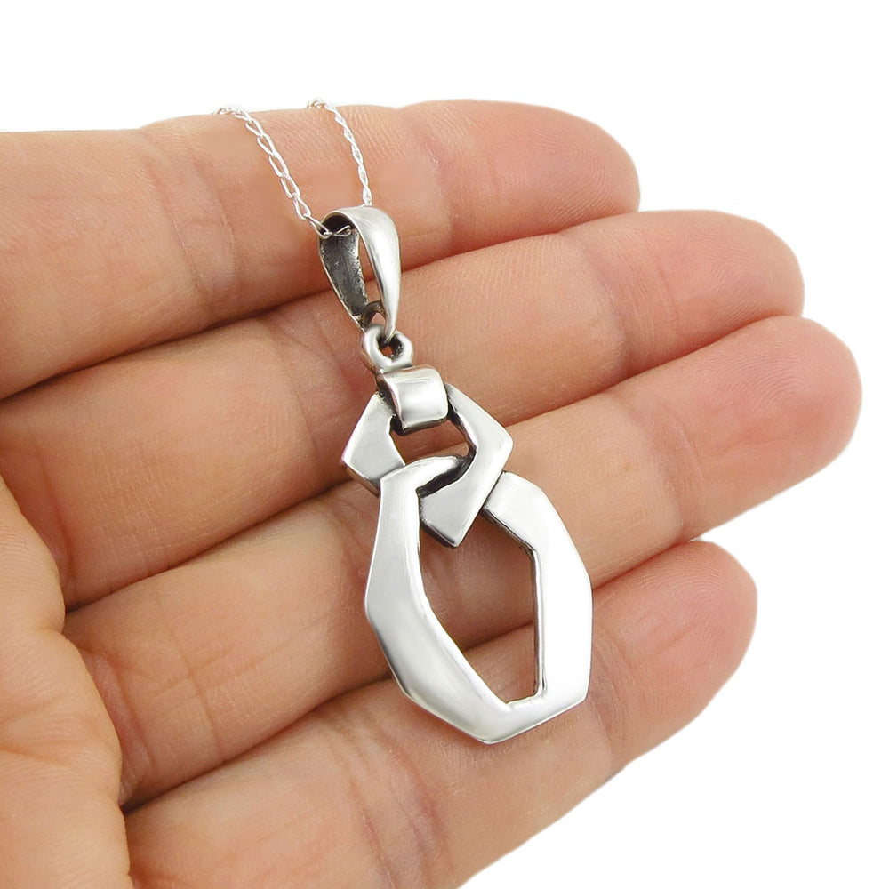 Handmade chunky 925 silver chain link pendant and curb chain necklace held in a hand against a white background