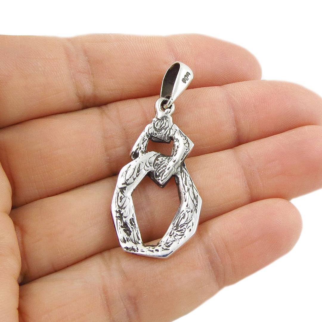 Silver pendant held upside down to reveal the 925 hallmark in a hand against a white background