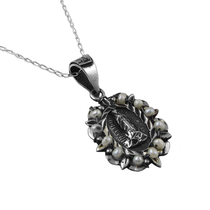 925 sterling silver handmade Mexican Maria Belen Nilson pendant and chain necklace with the virgin mary surrounded by seed pearls on a white background