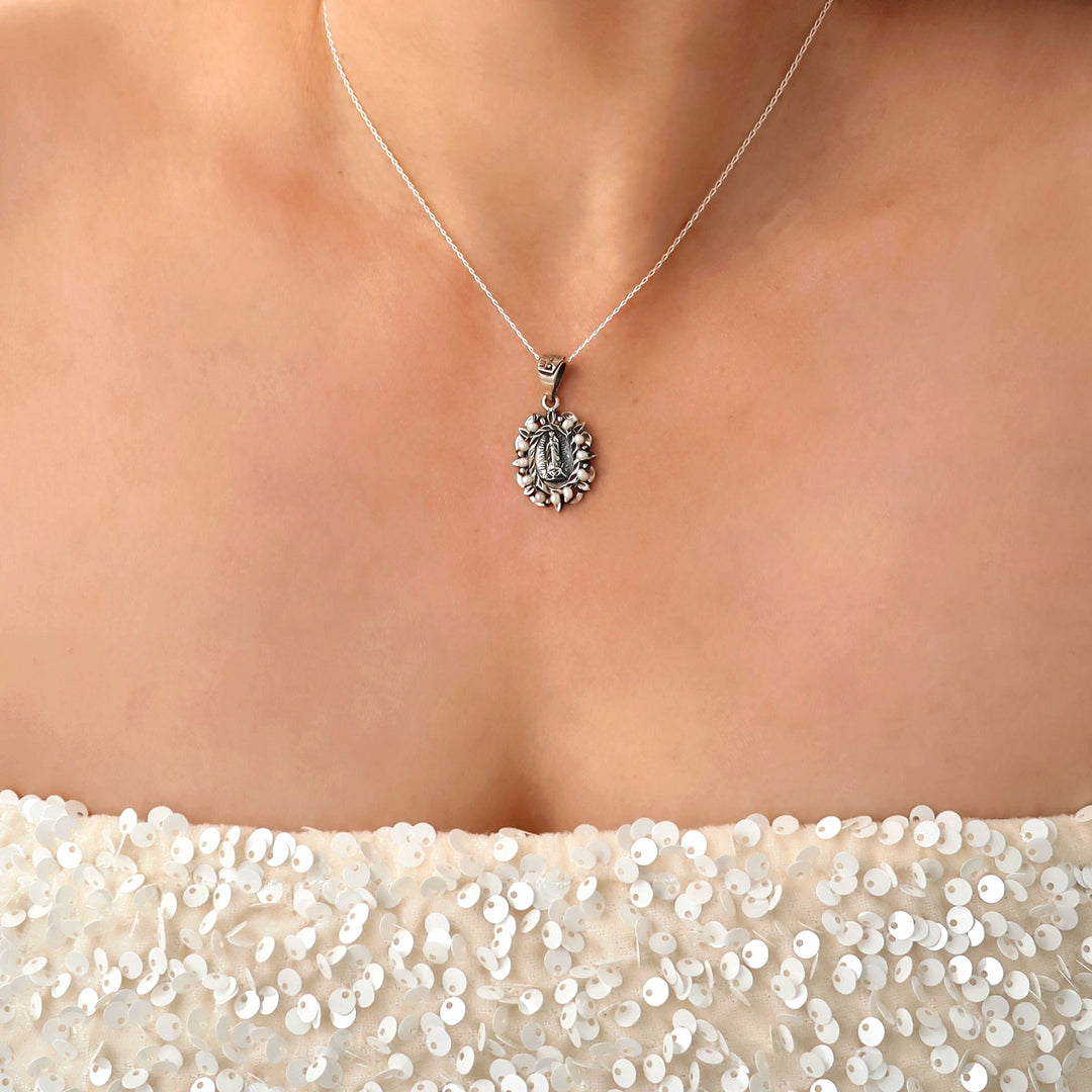 Woman in a sequinned top wearing a Baroque 925 sterling silver pendant and chain necklace featuring the Virgin Mary surrounded by seeds pearls