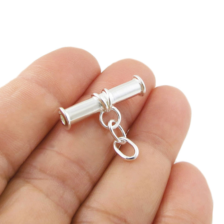 Sterling 925 Silver cylindrical albert t bar pendant charm held between a woman's fingers on a white background