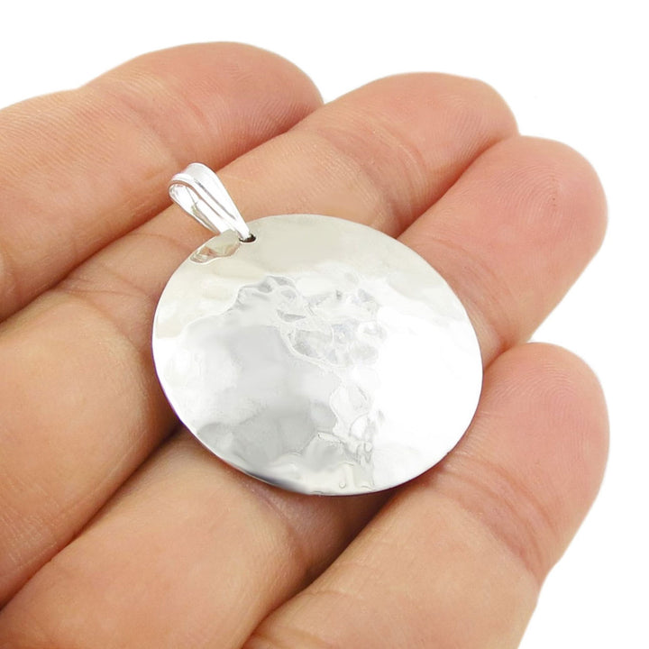 Hammered 925 sterling silver ladies pendant held in a hand against a white background