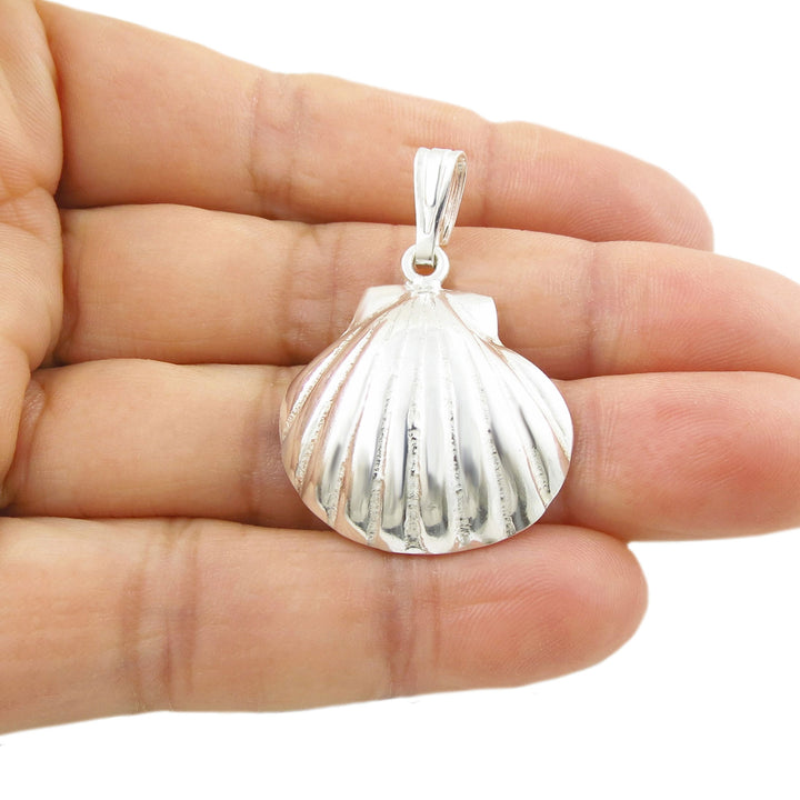 Sterling 925 Silver sea shell pendant jewelllery for women held in a hand against a white background