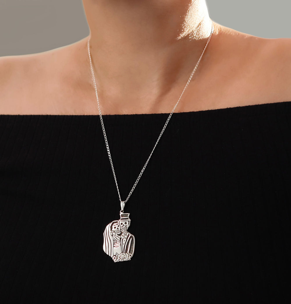 Sterling 925 Silver necklace with a Mexican day of the dead pendant on a long curb chain worn by a woman in a  black off the shoulder top