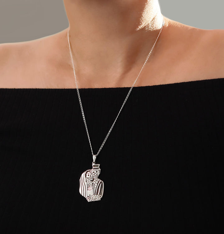 Sterling 925 Silver necklace with a Mexican day of the dead pendant on a long curb chain worn by a woman in a  black off the shoulder top
