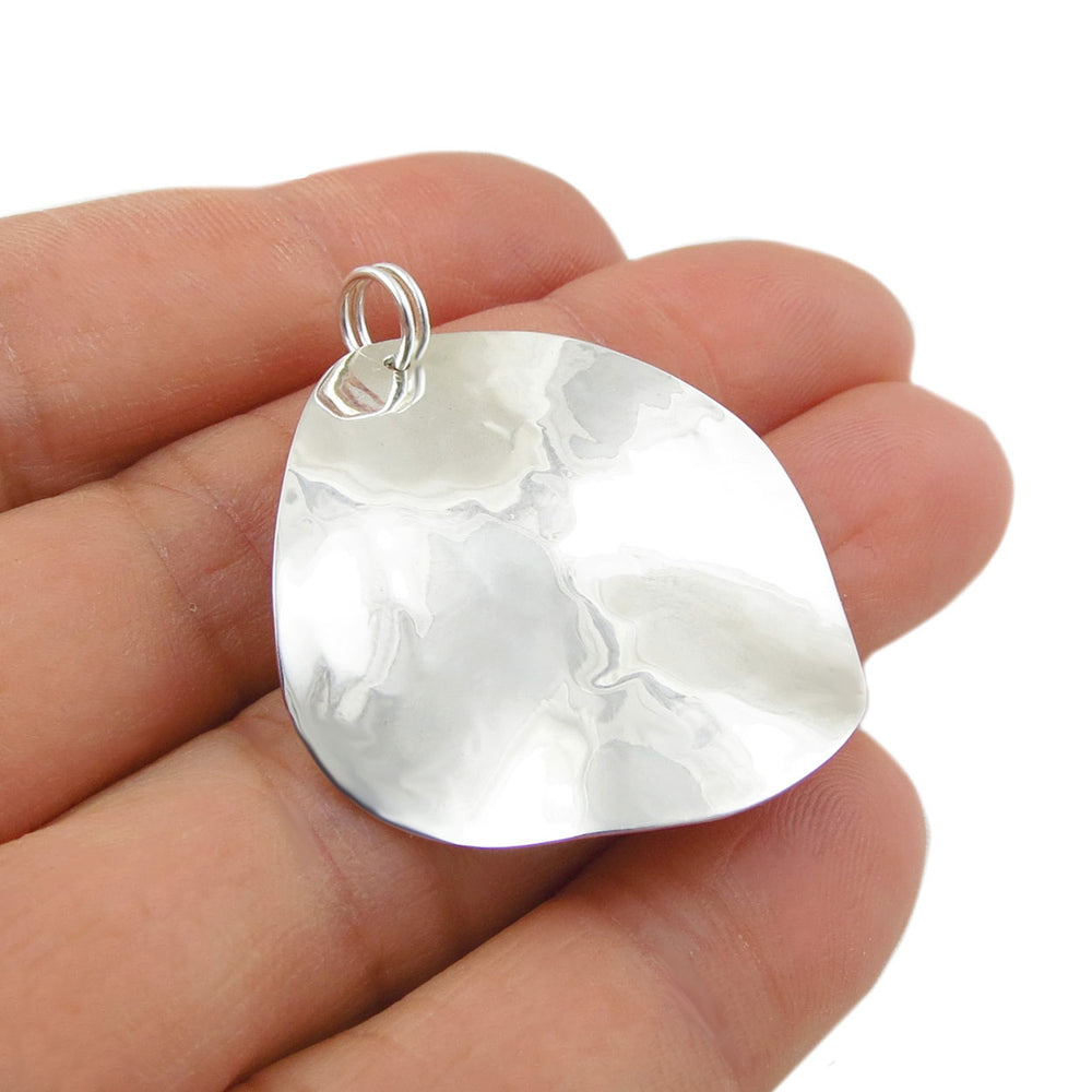 Hammered 925 Silver curved pendant jewellery held between fingers on a white background