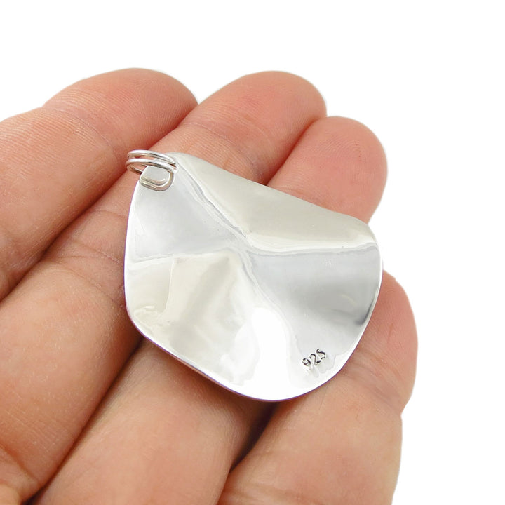 925 silver pendant jewellery held upside down to show the 925 halllmark held in a woman's hand against a white background