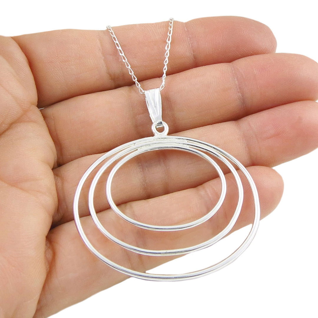 Large oval sterling 925 silver pendant and chain necklace held in a hand against a white background