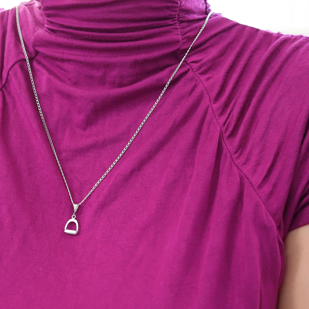 Sterling 925 Silver equestrian horse stirrup pendant and chain necklace worn by a woman in a purple turtleneck top 