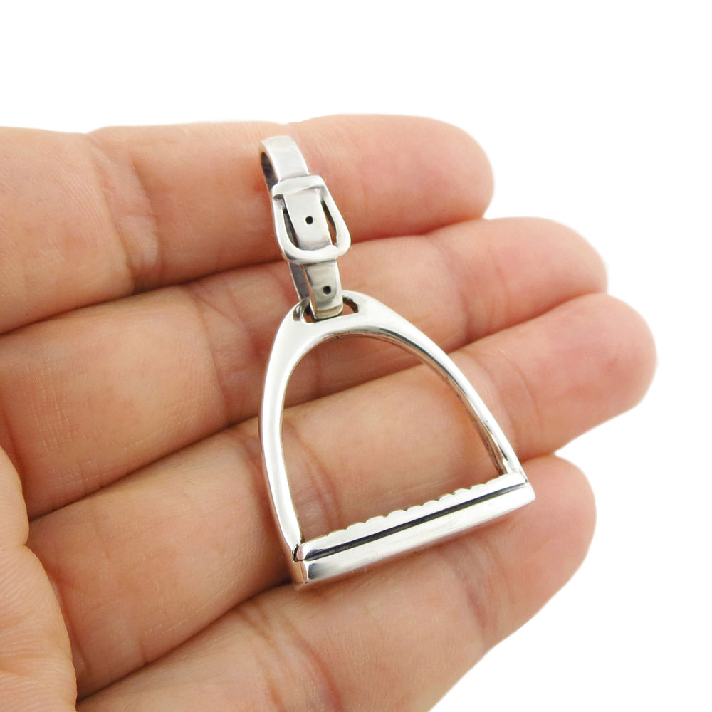 Equestrian sterling silver horse stirrup pendant jewellery held in a hand against a white background
