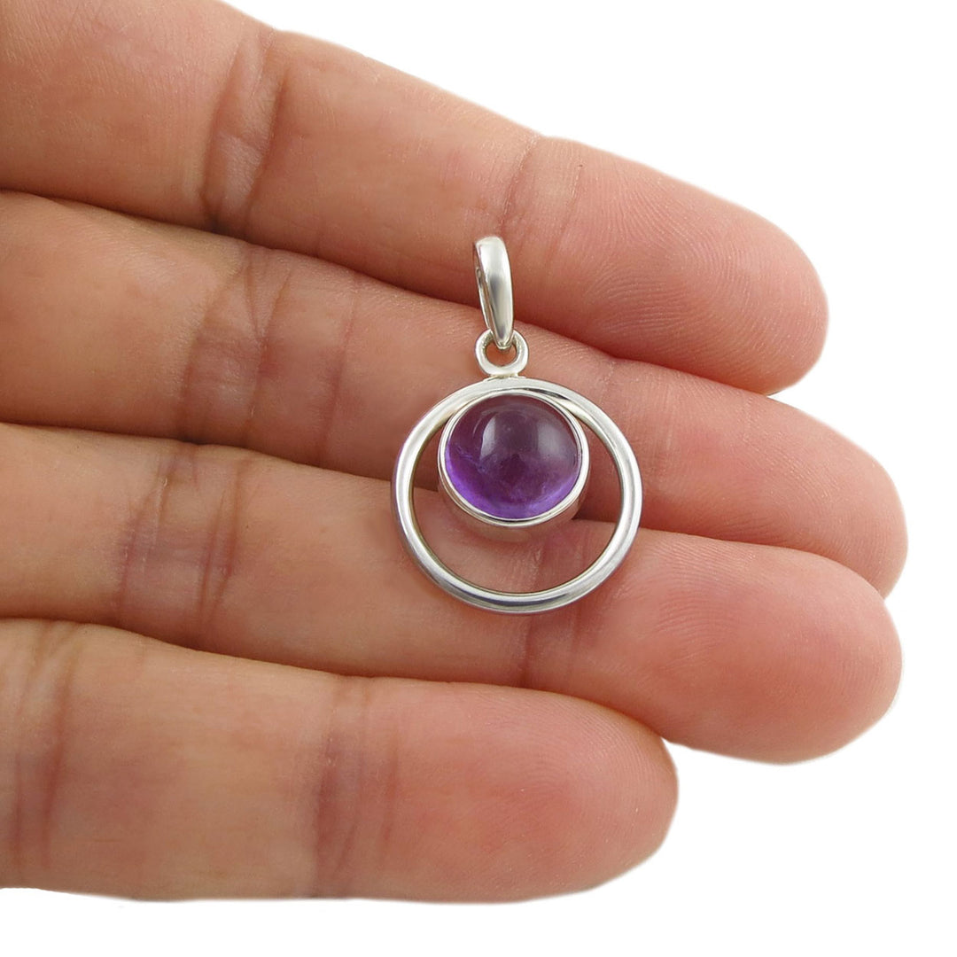 925 sterling silver pendant jewellery with a purple amethyst gemstone held between fingers on a white background