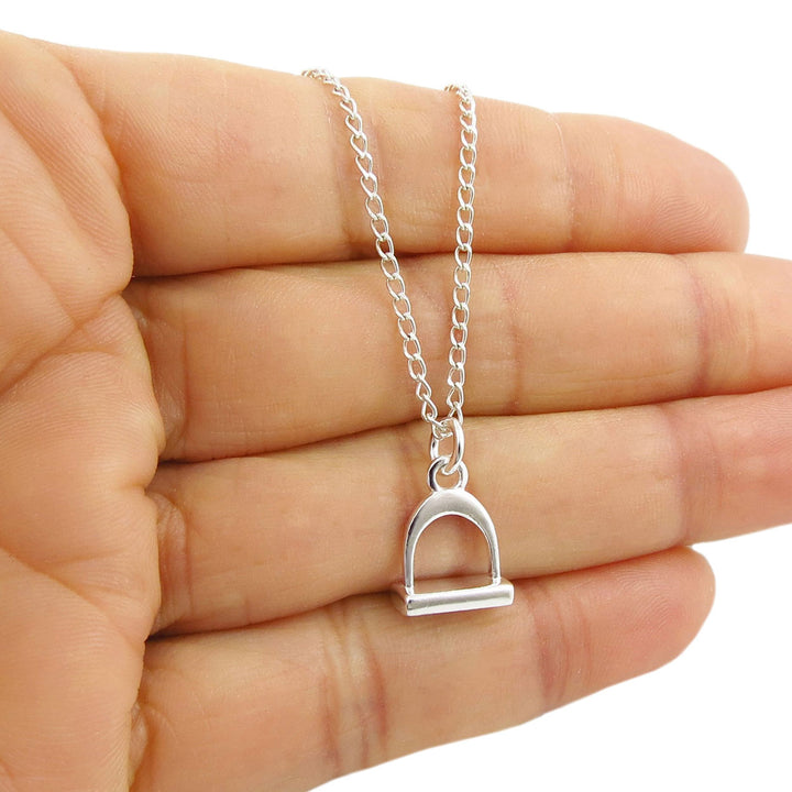 Sterling 925 silver curb chain necklace with a horse stirrup pendant held in a hand against a white background